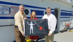 Ferry Division Director Harold Thomas, Blackbeard 300 Committee Chair LaRae Umfleet, and Ferry Division Deputy Director Jed Dixon display one of the Blackbeard flags