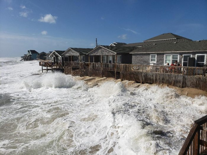High surf washes over the beach and onto the road on the north end of Buxton. Photo by Don Bowers, Island Free Press.